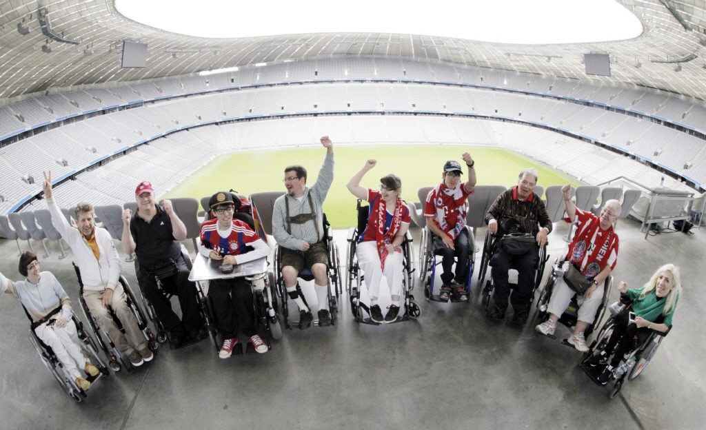 Gruppenbild der Rollstuhlfahrer*innen im Stadion mit Rängen und Rasen im Hintergrund