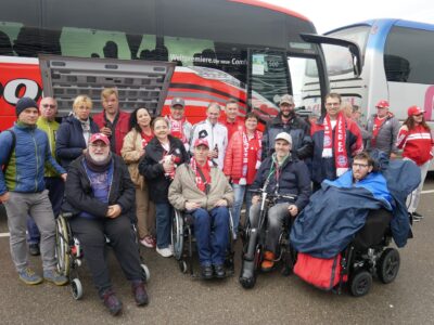 Bayern-Fans mit und ohne Rollstuhl vor einem Bus