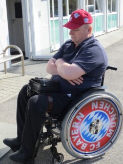 Uli mit Bayern-Cap schläft im Rollstuhl mit Bayern-Logo