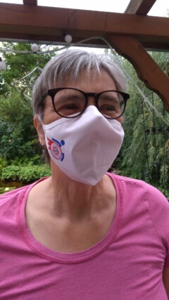 Frau mit Mund-Nasenschutz mit Rollwagerl-Logo in weiß