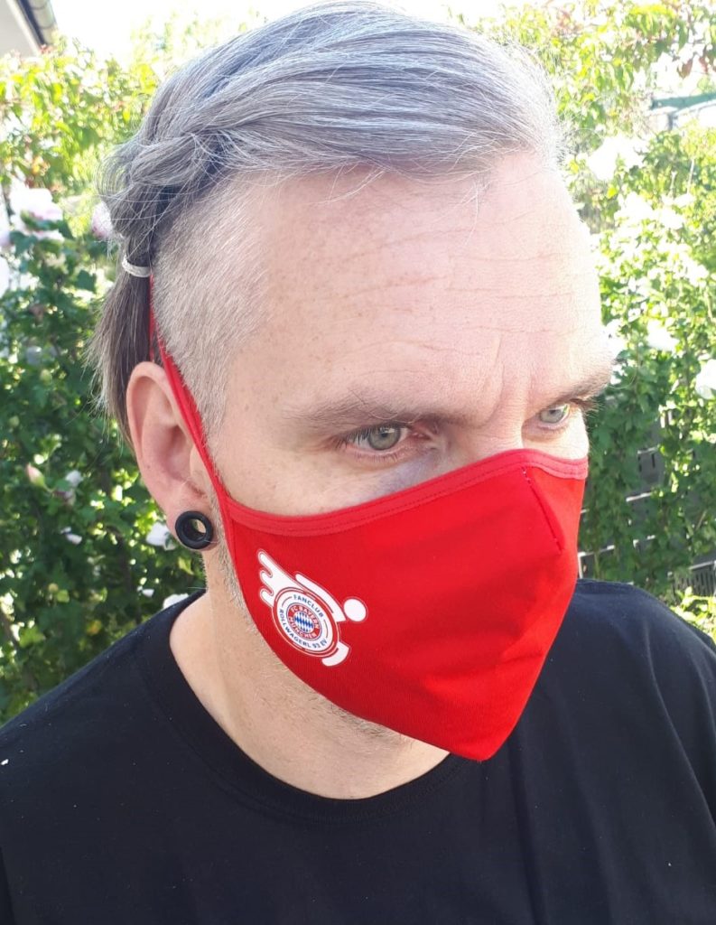 Mann mit Mund-Nasenschutz mit Rollwagerl-Logo in rot