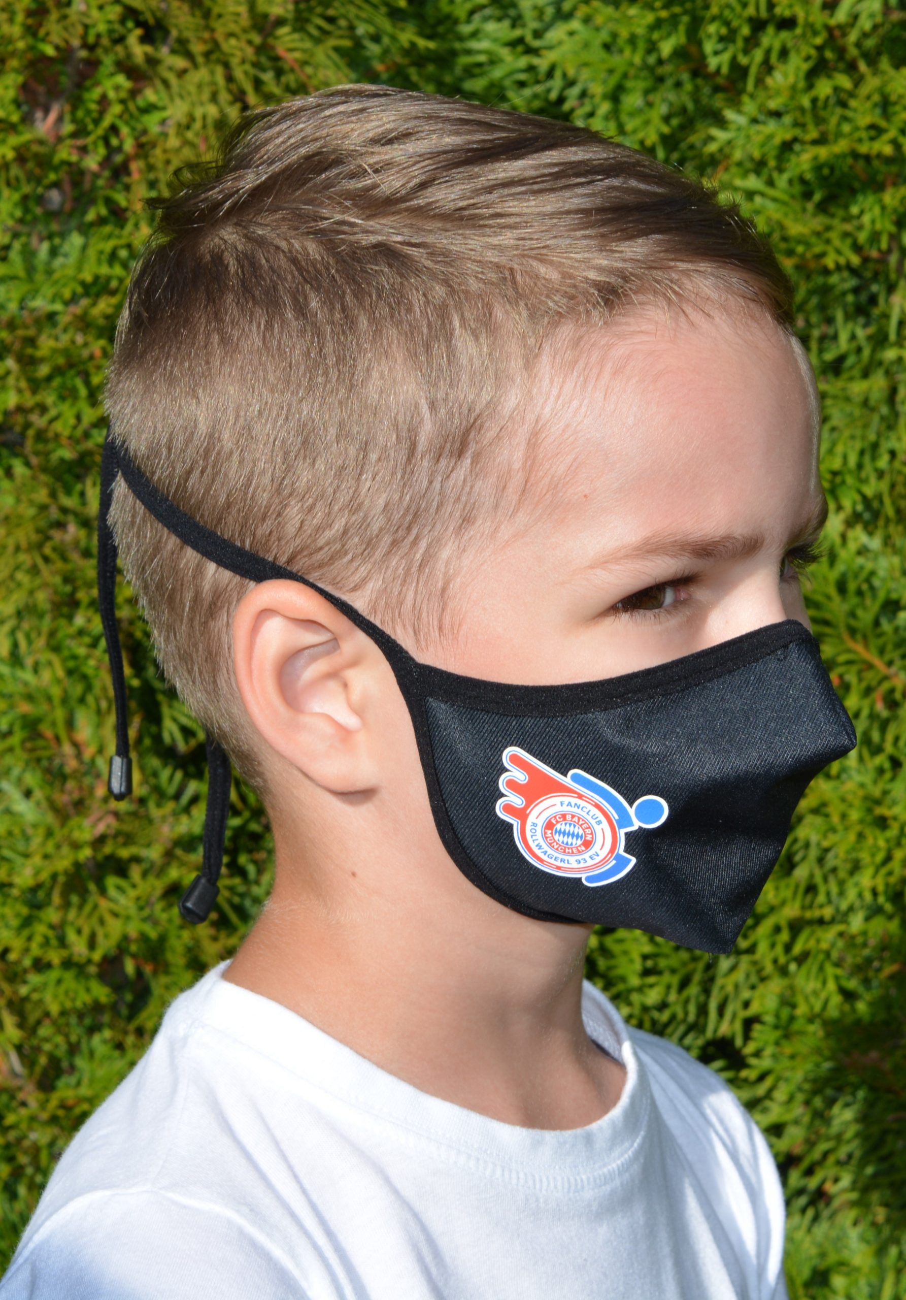 Kind mit Mund-Nasenschutz mit Rollwagerl-Logo in schwarz