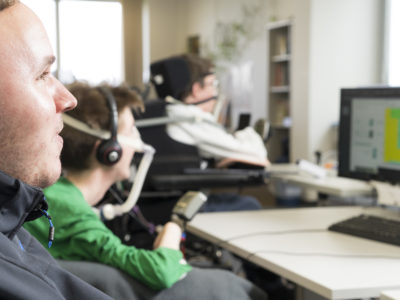 Drei körperbehinderte Männer an ihrem PC-Arbeitsplatz