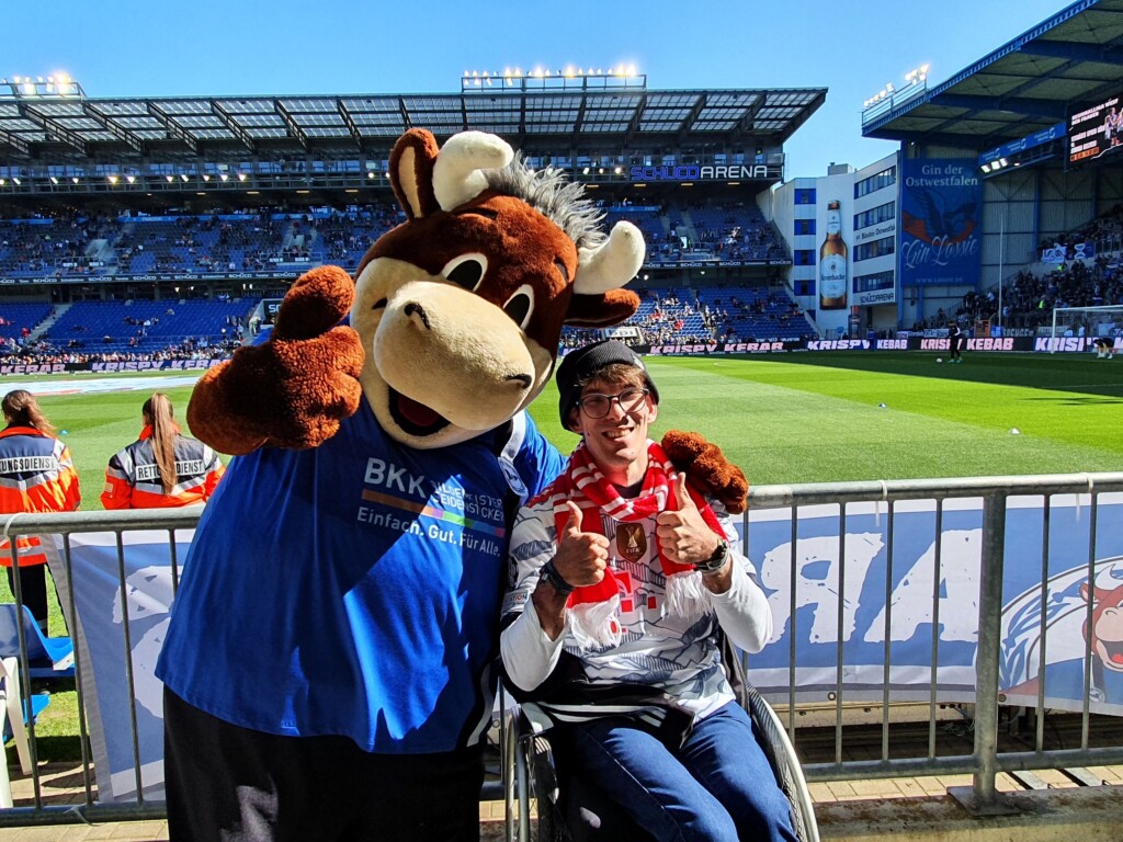 Mitglied Kevin Beik mit dem Maskottchen von Bielefeld im Stadion.