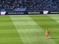 Das Rollwagerl Banner in einem Stadion das gefüllt mit Zuschauern ist. In der Mitte ist ein Spieler.