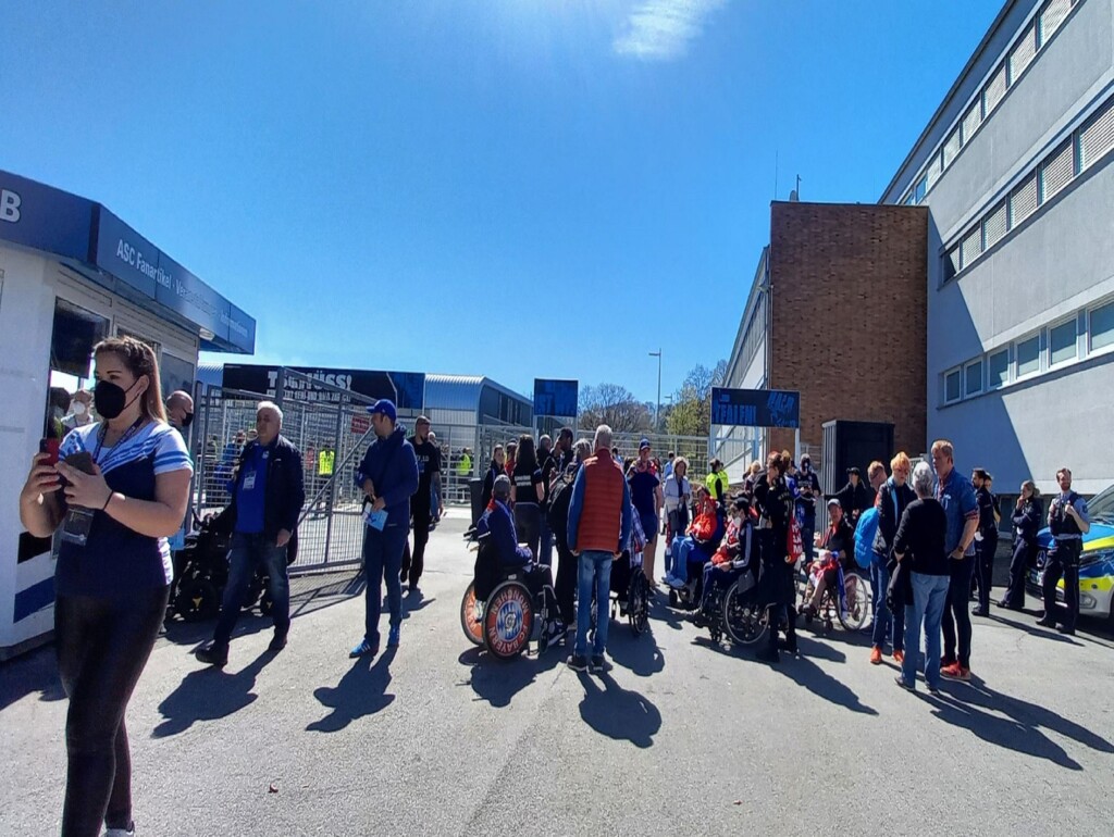 Eine Gruppe Menschen vor einem Tor am Stadion der Arminia in Bielefeld. Es sind auch Rollstuhlfahrer dabei.