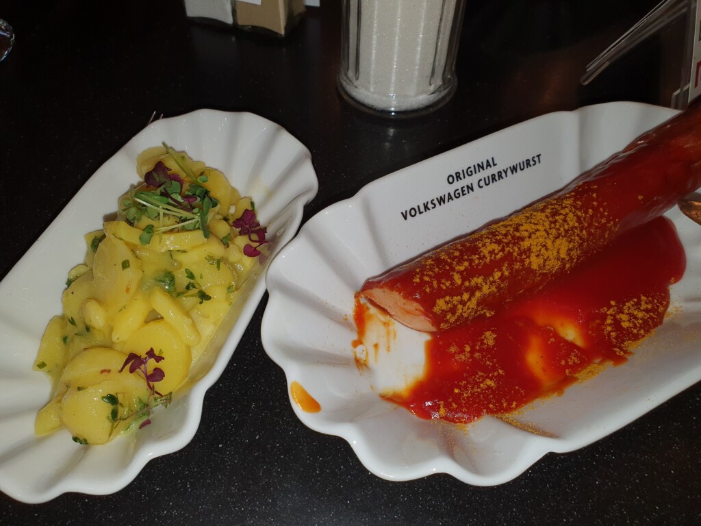 Currywurst in einem Teller mit einem Kartoffelsalat. Autostadt Wolfsburg.