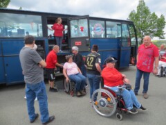 Ein Reisebus mit Rollstuhlfahrern. Die Türen sind geöffnet und die Hebebühne zum entladen der Rollstuhlfahrer ist im Einsatz.