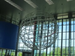 Eine Weltkugel aus Stahl hängt an der Decke in einem großen Gebäude