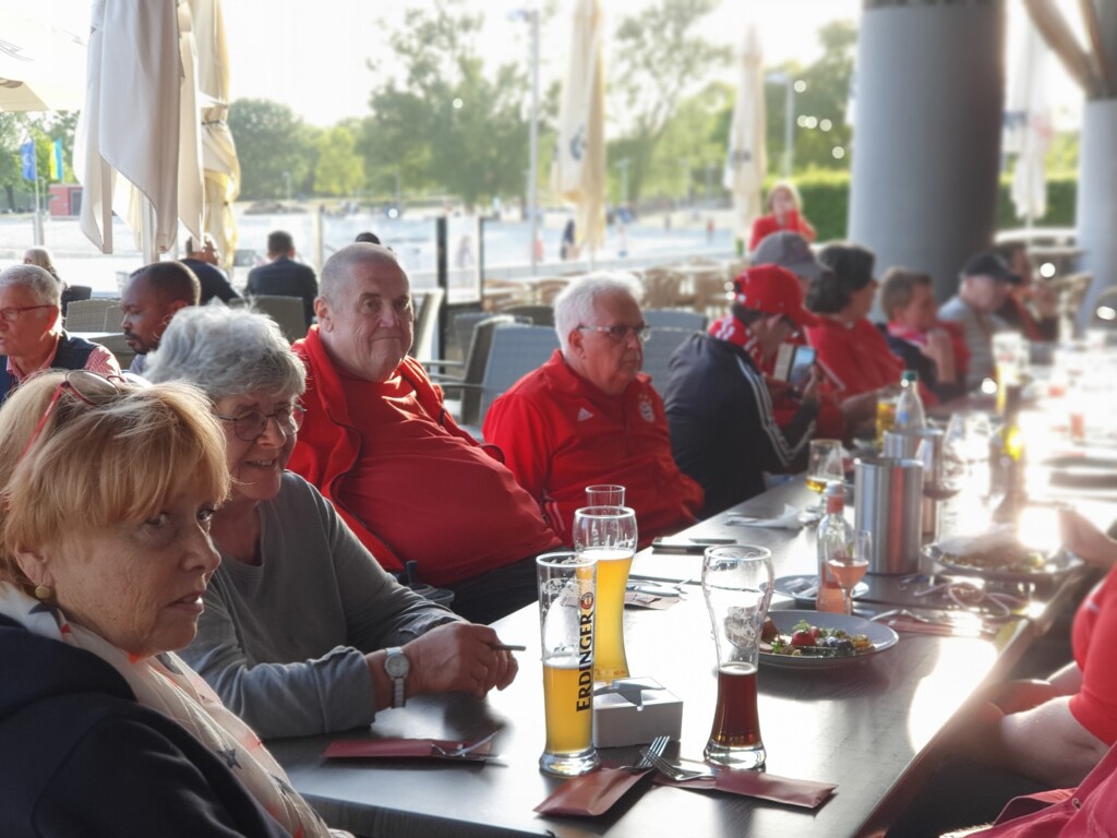 Menschen sitzen gesellig an einem Tisch im Außenbereich eines Restaurants