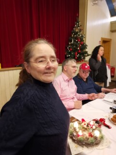 Zwei Frauen und zwei Männer an einem Tisch. Im Hintergrund ein Weihnachtsbaum.
