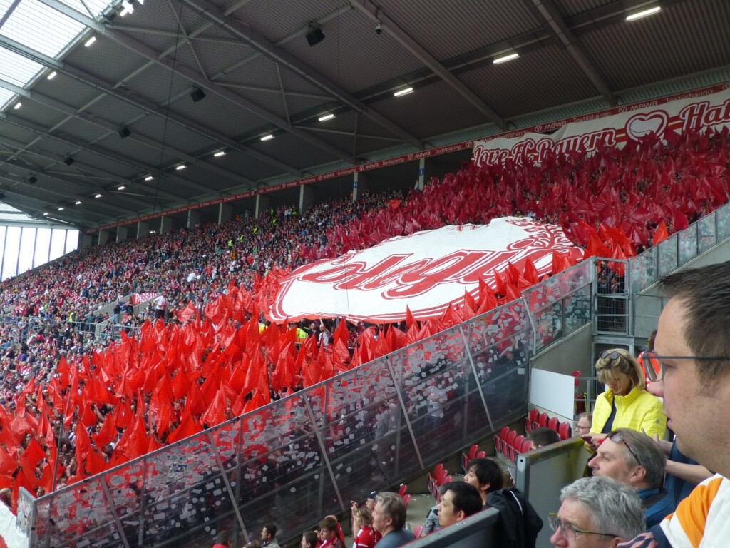 Bayern-Fans in einem Block. Alle halten rote Fahnen und auf einem Banner steht Love FC Bayern.