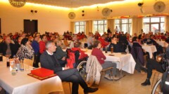 Ein Festsaal mit FC Bayern Fans. Darunter Rollstuhlfahrer