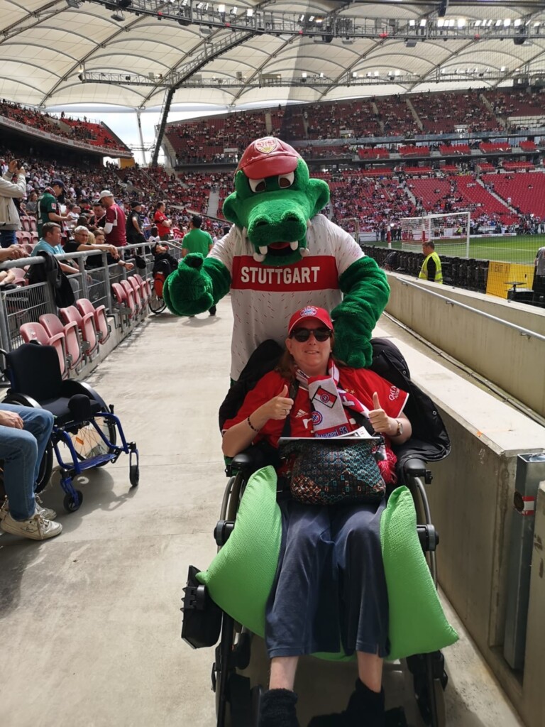 Eine Rollstuhlfahrerin mit dem Maskottchen des VfB Stuttgart im Stadion