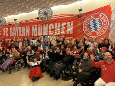 Ein Gruppenfoto vor einem großen FC-Bayern-München-Banner.