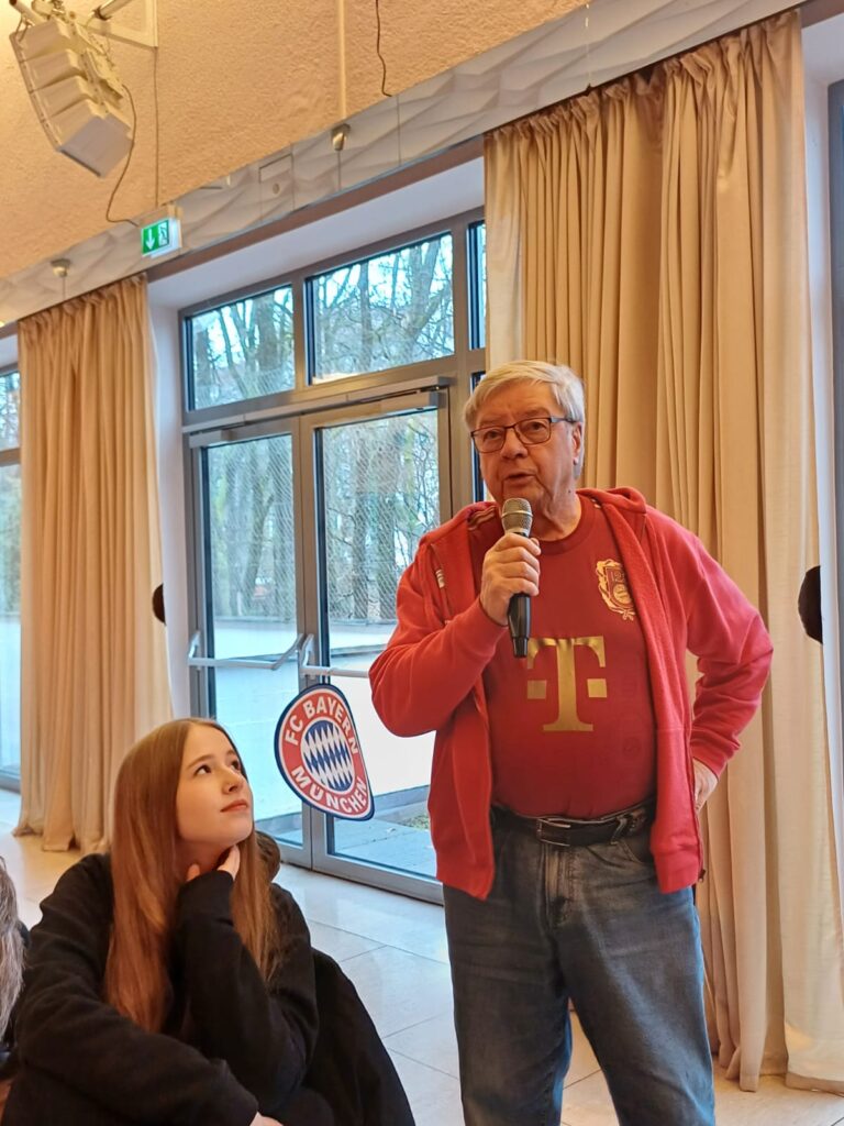 Peter Möws stellt mit Mikro in der Hand eine Frage an Max Eberl.